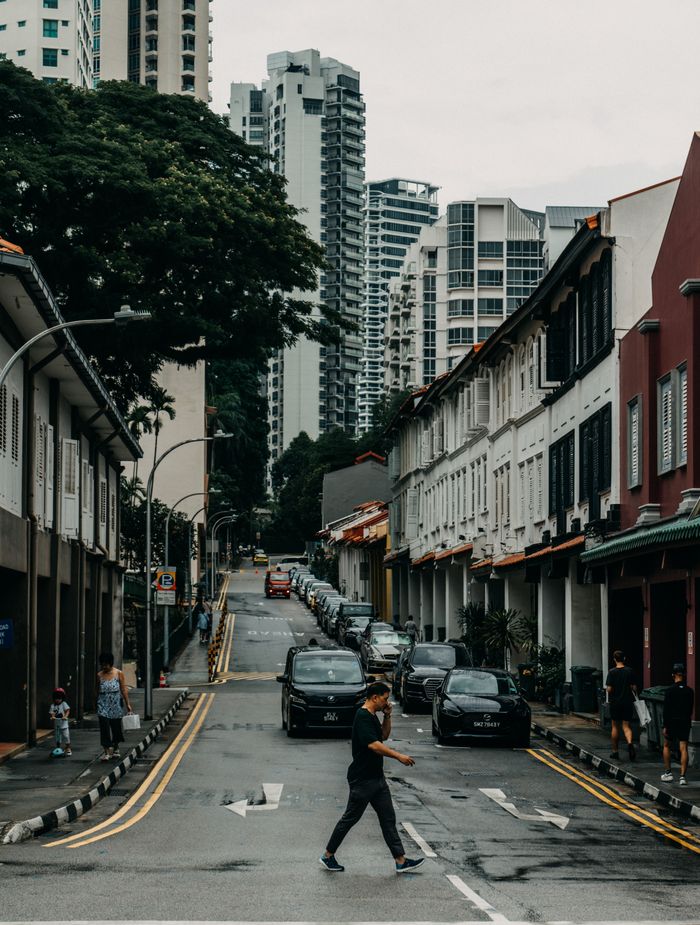 A bustling city street lined with shops, pedestrians crossing, and modern skyscrapers in the background.