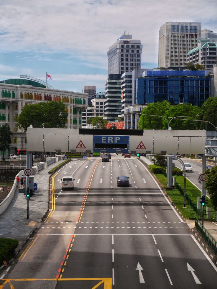 Busy roadway with Electronic Road Pricing gantry in downtown Singapore, showcasing urban architecture.