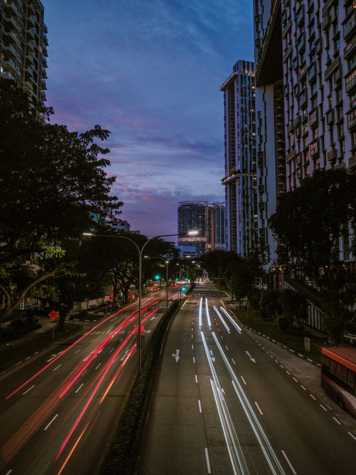 Vibrant city view at twilight featuring light trails on a busy road.